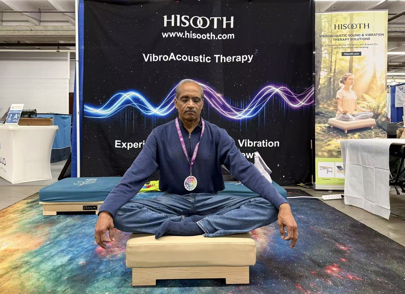 Visitor experiencing vibroacoustic meditation platform at wellness exhibition